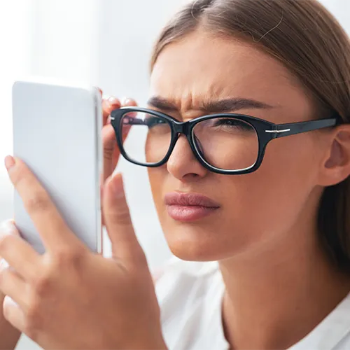 mulher jovem com óculos forçando a vista, baixa visão nos hospitais de olhos da Rede Vision One