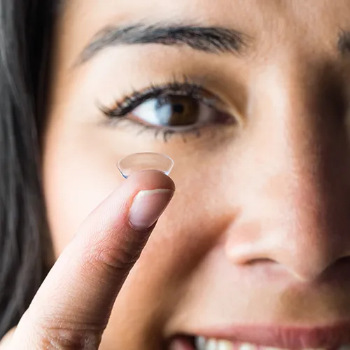 mulher segurando com um dedo as lentes de contato